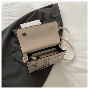 Détail du sac bandoulière blanc à motifs cerises montrant la capacité de rangement interne