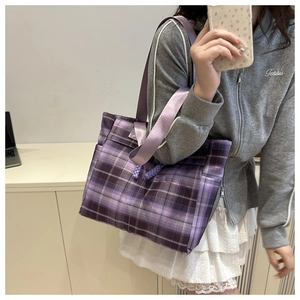 Detail of purple plaid canvas tote bag featuring woven drawstrings and wide fabric strap