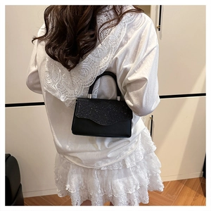 Detail of elegant black evening handbag with glitter wavy flap and metal chain strap