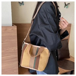 Detailed texture of a woven tote bag with vertical earth-tone stripes and fabric straps