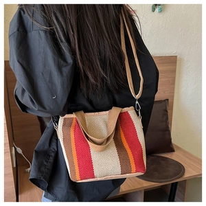 Détail d'un sac à main tissé à rayures colorées posé sur un banc en bois en intérieur