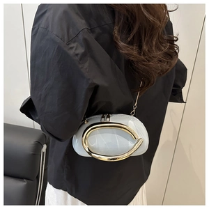 Detail of light blue patent leather crossbody bag with a large gold ring buckle and chain