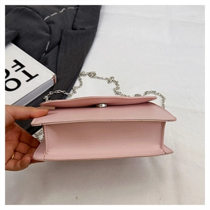 Detail of the pink crossbody bag interior with silver chain strap and magnetic snap closure