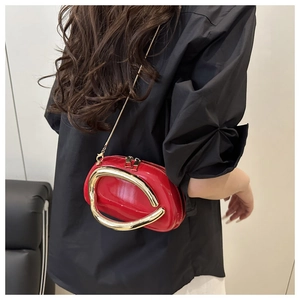 Close-up of a glossy red patent leather barrel bag featuring a gold oval metal handle