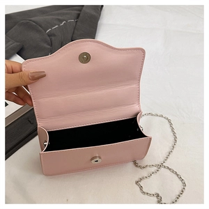 Detailed view of pink shoulder bag showing wavy edge lid, magnetic closure and black lining