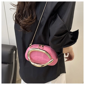 Close-up of pink patent leather handbag with gold metal C-handle and chain strap
