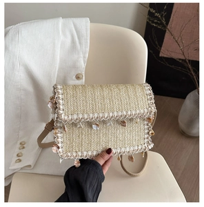 Detail view of woven straw bag featuring shell pendants and white lace wave trim details