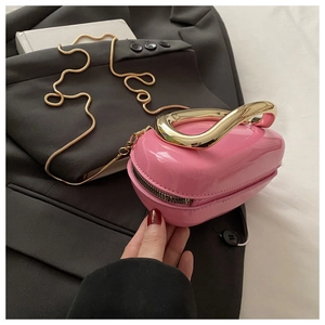 Detailed macro of pink patent leather handbag with a twisted gold metal handle and chain
