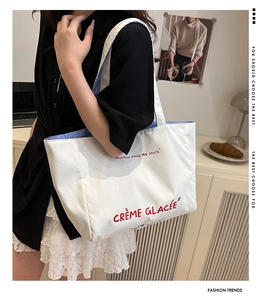 Close-up of a white tote bag featuring red French lettering and striped lining detail