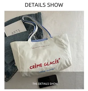 Detailed shot of white canvas tote bag with French typography and blue striped lining