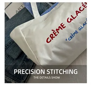 Close-up of precise stitching on cream canvas tote bag with Crème Glacée text design