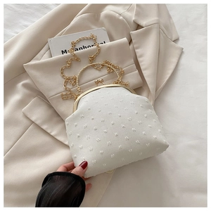 Detail of cream vintage shell bag with textured fabric and golden ring handle