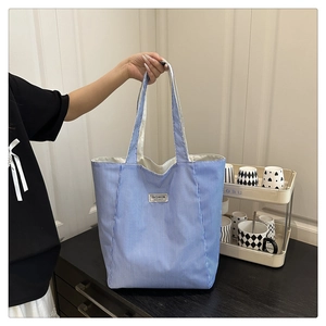 Close-up of blue and white striped canvas tote bag with woven Fashion Instinct label