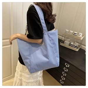 Detail shot of blue and white striped canvas tote bag with fashion label on shoulder