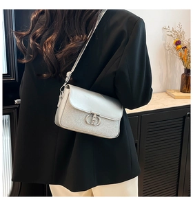 Détail du sac bandoulière argenté avec logo en métal et texture en cuir mélangé