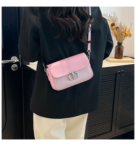 Détail d'un sac bandoulière rose en patchwork avec fermoir rotatif argenté sur un mannequin