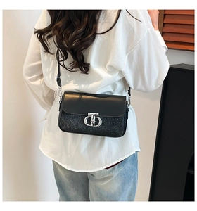 Détail d'un sac bandoulière en cuir noir avec texture pailletée et fermoir argenté chic