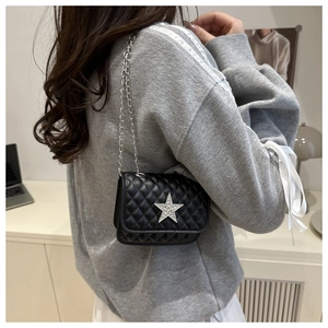 Dettaglio della mini borsa trapuntata nera con stella d'argento e tracolla a catena sulla spalla