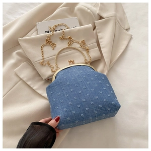Dettaglio borsa a conchiglia in denim blu con trama trapuntata e chiusura oro