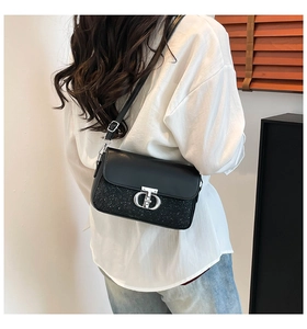 Détail d'un sac bandoulière noir chic avec fermoir argenté et texture à paillettes