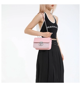 Close-up of pink leather handbag featuring glitter trim and silver double ring buckle