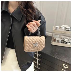 Detail of beige quilted crossbody bag with a sparkling silver star logo and metal chain