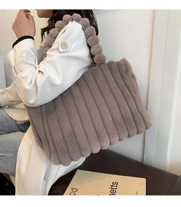 Detail of faux fur tote bag with striped texture and plush ball handle in taupe grey