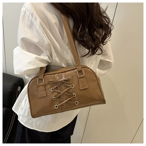Brown leather retro shoulder bag with unique cross-strap design and gold eyelet details