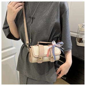 Detail of cylindrical woven bag with leather trim and decorative plaid lace bow