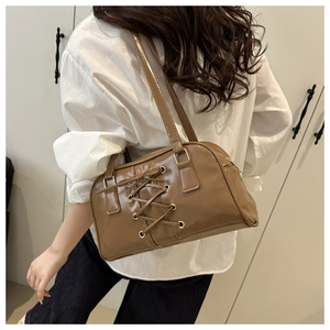 Detail of caramel brown glossy leather shoulder bag with corset lace-up metal eyelets