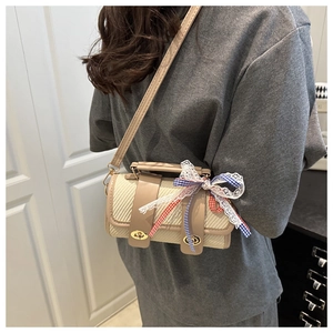 Detail of woven cylinder crossbody bag with leather strap and decorative lace bow
