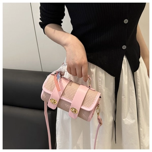 Détail d'un sac cylindrique tissé rose avec ruban en dentelle et fermoir doré