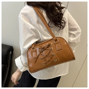 Close-up of caramel brown shoulder bag with lace-up detail and glossy PU leather texture