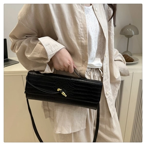 Elegante borsa baguette nera in coccodrillo indossata da una modella in posa