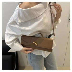 Detailed side view of a brown crocodile pattern baguette bag with a gold metal lock buckle