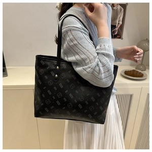Close-up of the black leather tote bag featuring repeating cartoon bear and letter prints