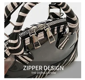 Close-up of dual silver zippers and zebra print handle on the textured shell handbag