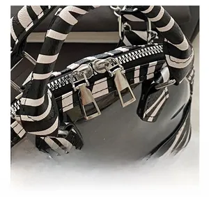 Close-up of dual silver zippers and zebra print handle on the textured shell handbag