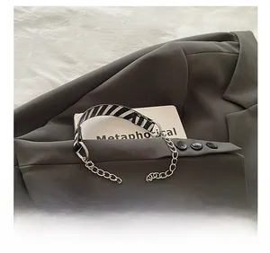 Detail of black and white striped canvas strap with silver metal chain links on blazer