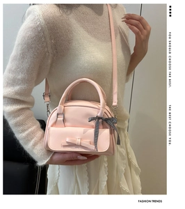 Pale pink handbag detail with a cute bow and checkered ribbon strap shown on model