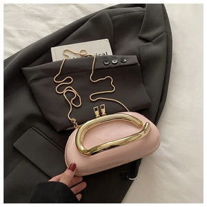 Détail d'une pochette en cuir verni rose pâle avec poignée dorée et bandoulière chaîne