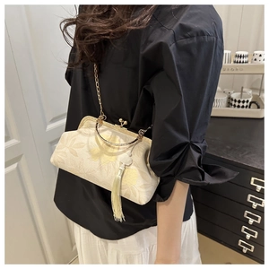 Detail of white jacquard clutch bag with flower pattern, metal frame and long tassel