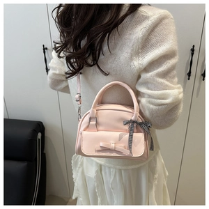 Pink bow handbag with adjustable shoulder strap shown in a lifestyle setting