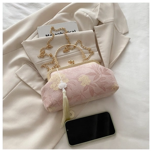 Détail de la pochette de soirée en brocart rose avec poignée en métal et pompon