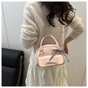 Detail of pink bow shell bag showing the stylish ribbon and leather texture on a model