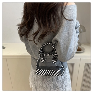 Detail of transparent PVC shell bag featuring zebra print base and silver chain strap