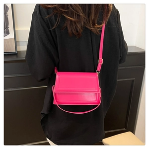 Detalle del bolso bandolera rosa magenta con correa ajustable y solapa en la modelo