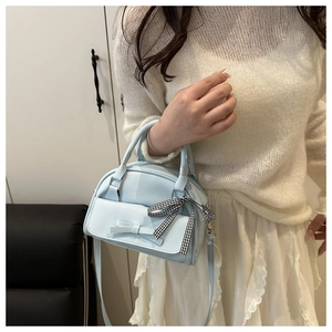 Close-up of light blue mini handbag with bow detail and stylish black checkered ribbon