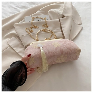 Détail du sac à main en soie rose à fleurs avec fermoir doré et pompon blanc
