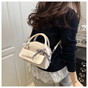 Chic cream white small square bag worn crossbody featuring a bow and checkered ribbon